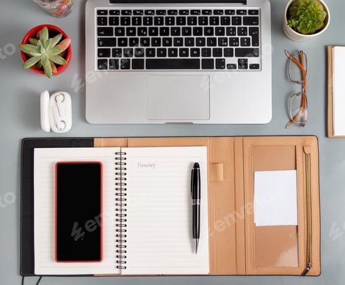 Preview: Laptop, cell phone and opened agenda on a grey desk top view