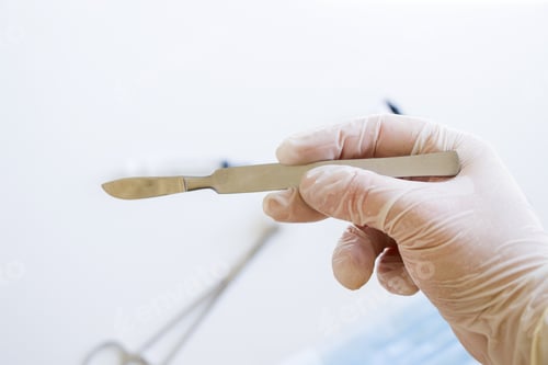 Preview: Closeup shot of a gloved hand holding a surgical scalpel