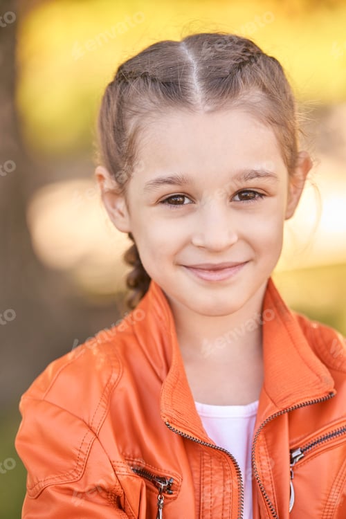 Preview: Smiling caucasian young girl in orange jacket outdoors with braided hair