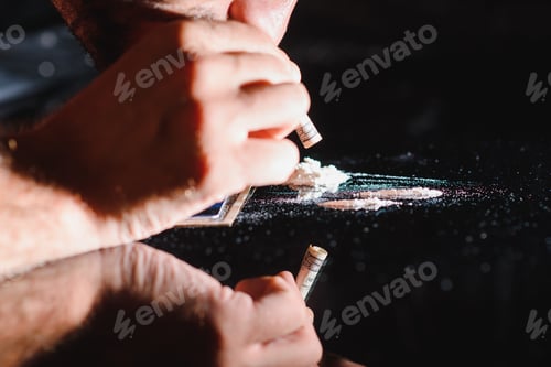 Preview: Close up of young drug dealer sniffing drug through rolled one hundred dollar bill from phone
