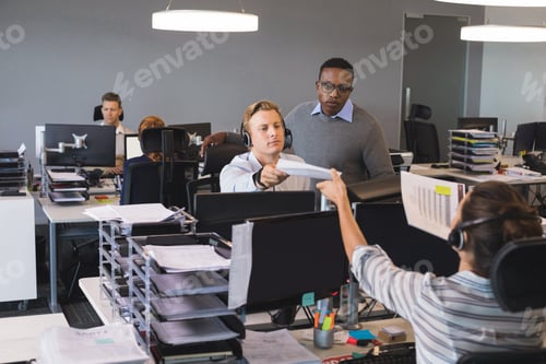 Preview: Businessman giving document to colleague working at office
