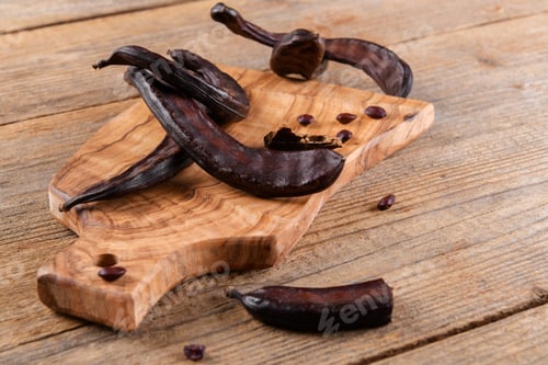 Preview: Dry raw carob pods on wooden background