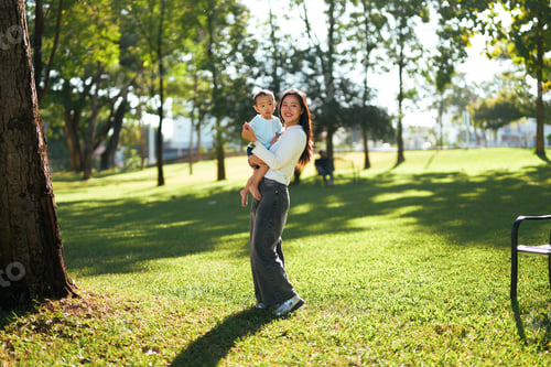 Preview: Mother holding baby while enjoying park outdoors