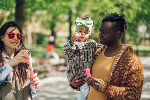 Preview: Multiracial family blowing soap bubbles in park