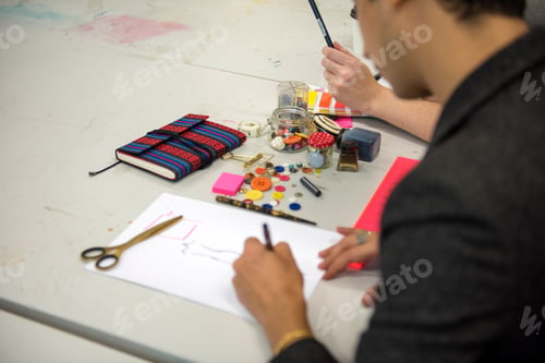 Preview: Craft time an artist sketches out designs amid a colorful array of crafting materials.