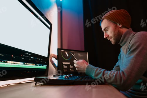 Preview: Male Video Editor sitting at his Computer using phone blank screen