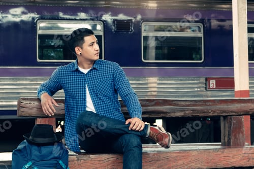 Preview: Backpacker man sitting on bench waiting at train station.
