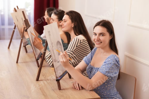 Preview: Group of women with easels learning to draw at wooden table in class