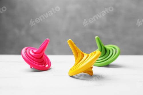 Preview: Bright spinning tops on white table, closeup