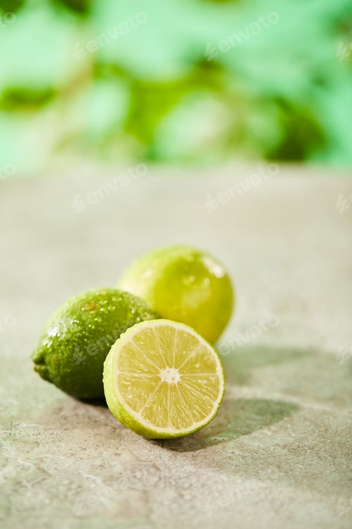 Preview: selective focus of whole and cut limes with drops on marble surface