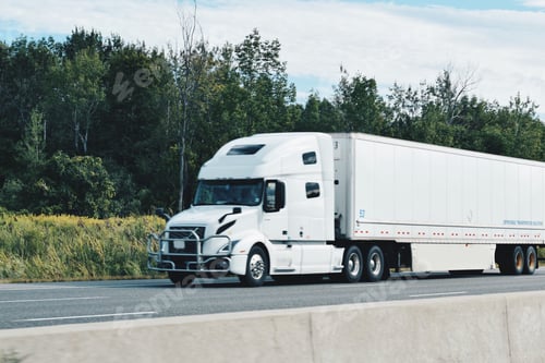 Preview: All white tractor trailer driving on a highway transporting and delivering goods and shipments