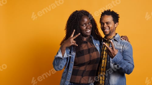 Preview: Cute life partners posing in studio and doing peace sign in studio