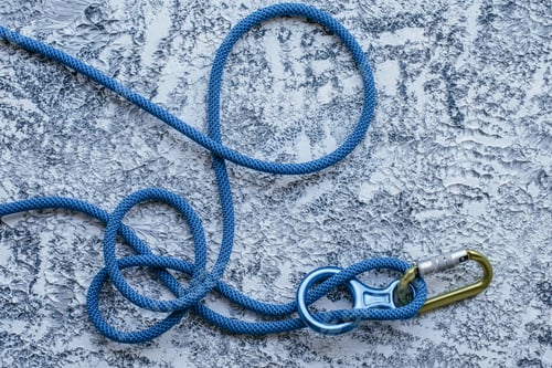 Preview: Isolated photo of climbing equipment. Part of carabiner lying on the white and grey colored surface