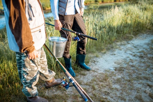 Preview: Holding fishing rods and bucket with fish outdoors