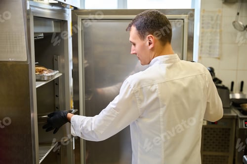Preview: Cook wearing protective gloves puts container of food in refrigerator