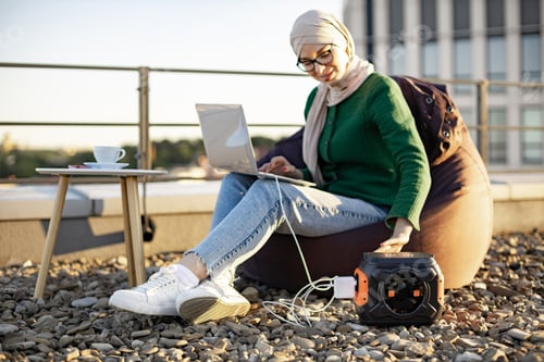 Preview: Person in hijab fixing charge cord from battery to computer