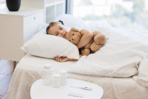 Preview: Little girl with virus resting on comfy bed with toy bear