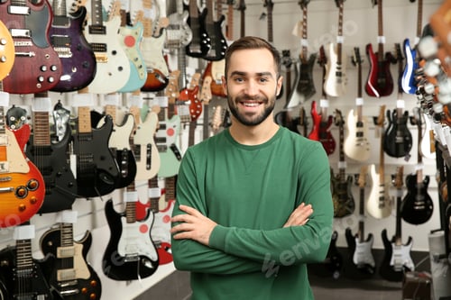 Preview: Young shop assistant near guitars in music store