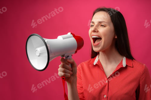 Preview: Young brunette woman shouting in megaphone against pink background