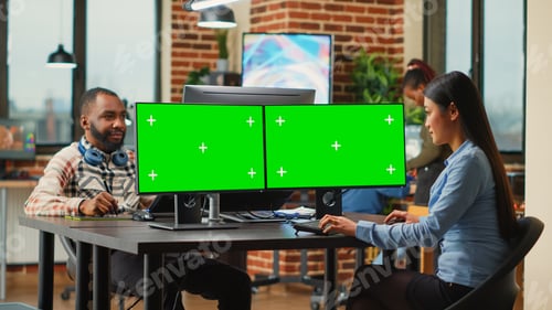 Preview: Asian digital editor looking at greenscreen on multiple monitors
