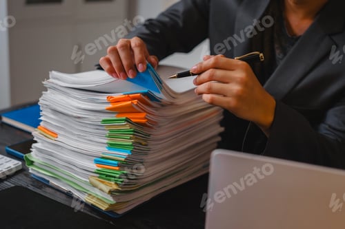 Preview: A businessman sits at his desk, working late into night on his laptop.reviews documents carefully