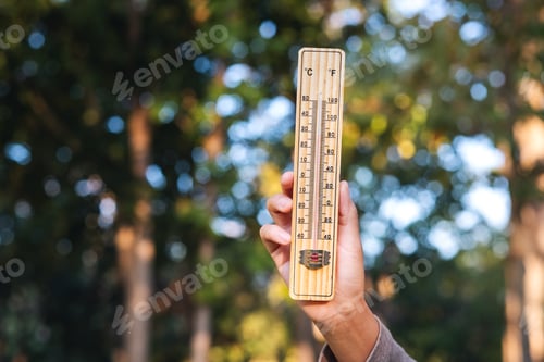 Preview: A hand holding thermometer in blurred nature background