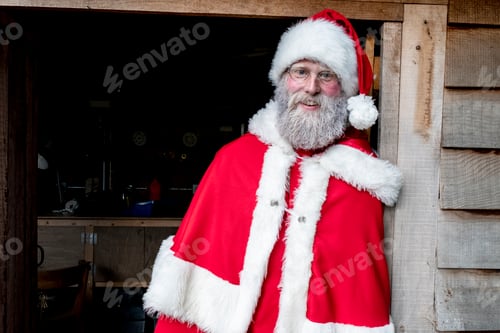 Preview: Man wearing Santa Claus costume standing in workshop doorway, looking at camera.