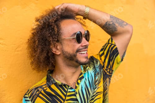 Preview: Man with afro hair in summer summer in a palm tree shirt on a yellow background