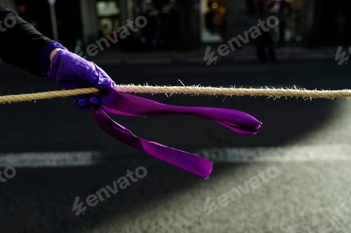 Preview: Purple tie tied to an agreement and grabbed by a woman's hand during a feminist protest.