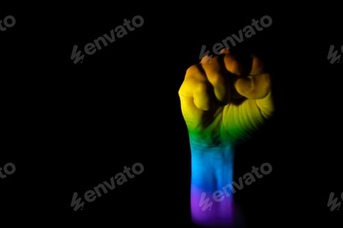 Preview: Raised fist illuminated with the LGBT pride flag on a black background with space for text