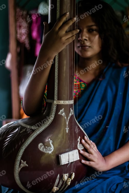 Preview: Middle-aged Indian woman holding an Indian musical instrument tanpura or sitar