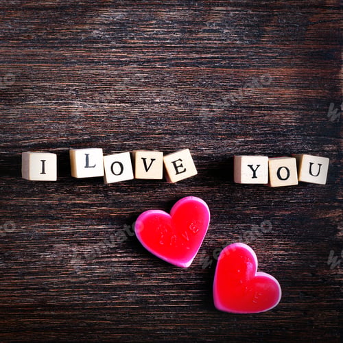 Preview: Heart shaped chewing candies and words I love you on cubes, wooden background. Free space for your
