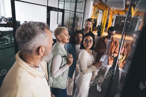 Preview: Multiracial coworkers standing near glass wall in hallway