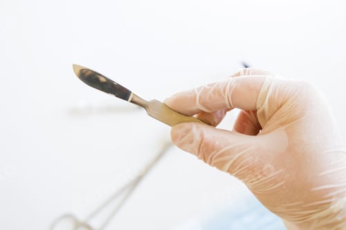 Preview: Closeup shot of a gloved hand holding a surgical scalpel