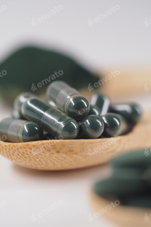 Preview: Spirulina capsules on a wooden spoon in a simple setting