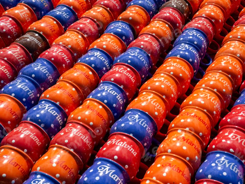 Preview: High angle shot of colorful mugs with random names of people for sale