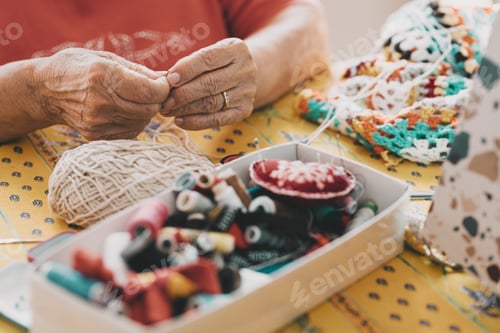 Preview: Close up of old mature woman hands working with crochet and sewing thread. Elderly indoor