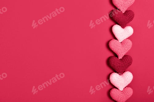Preview: Knitted hearts in a row lie on a red background. Background for Valentine's Day.