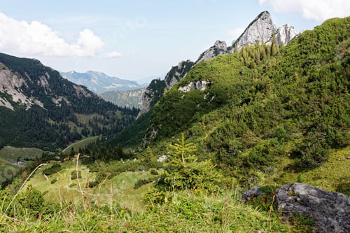 Preview: Lush green mountain landscape with rocky peaks.