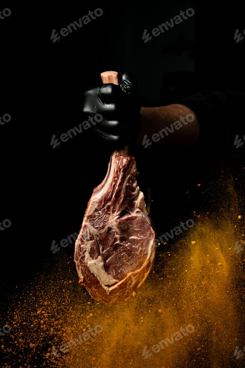 Preview: Vertical shot of a person holding a piece of raw meat with seasoning