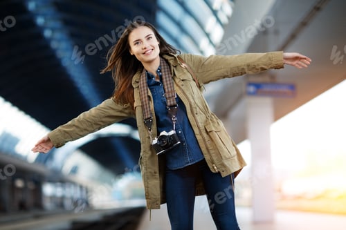 Preview: Happy young woman waitng train on the railway station platform.