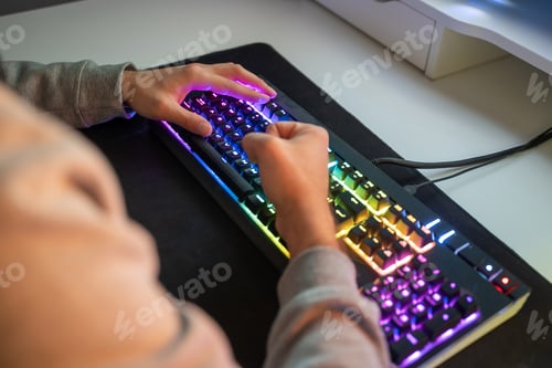Preview: Caucasian man using the keyboard of his gamer computer with LED lights and playing games