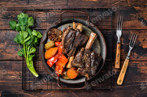 Preview: Homemade Braised Lamb Shanks with Sauce and Herbs in a steel tray. Wooden background. Top view. Copy