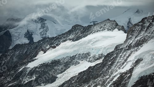 Preview: Snow-covered mountain range with low-hanging clouds