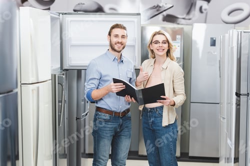 Preview: smiling consultant holding folder and woman showing like in home appliance store