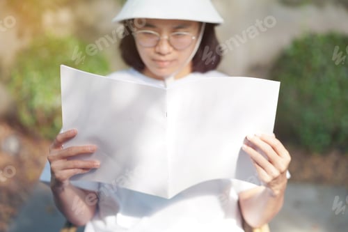 Preview: Close up and selective focus teenage gril holding and reading mock up book at garden