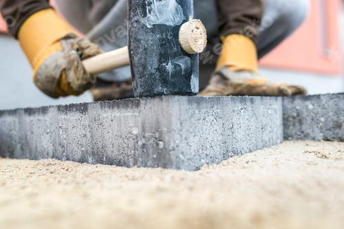 Preview: Builder tamping down a new paving slab or brick
