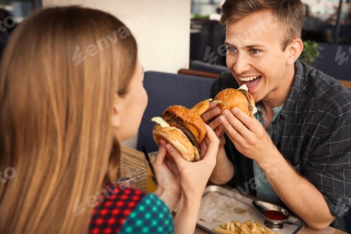 Preview: Young couple eating burgers in street cafe