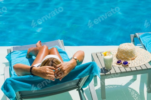 Preview: Pretty blond woman enjoying a cocktail at the pool