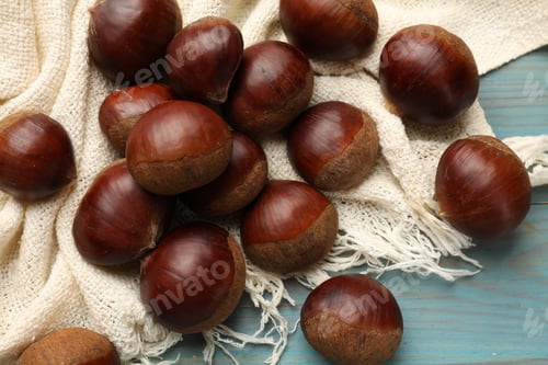 Preview: Roasted edible sweet chestnuts on light blue wooden table, flat lay